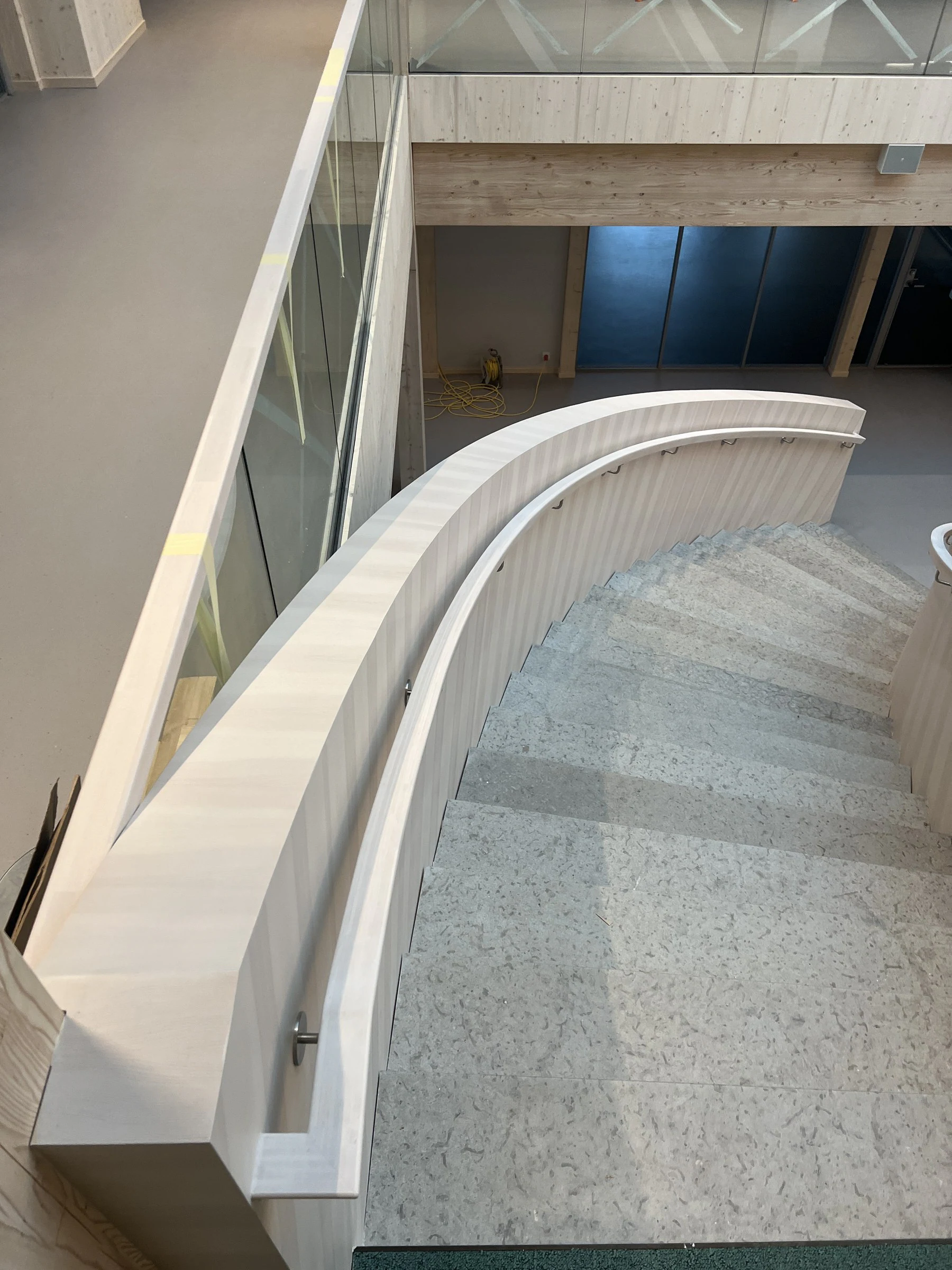 Curved pale timber staircase and sweeping handrail viewed from above