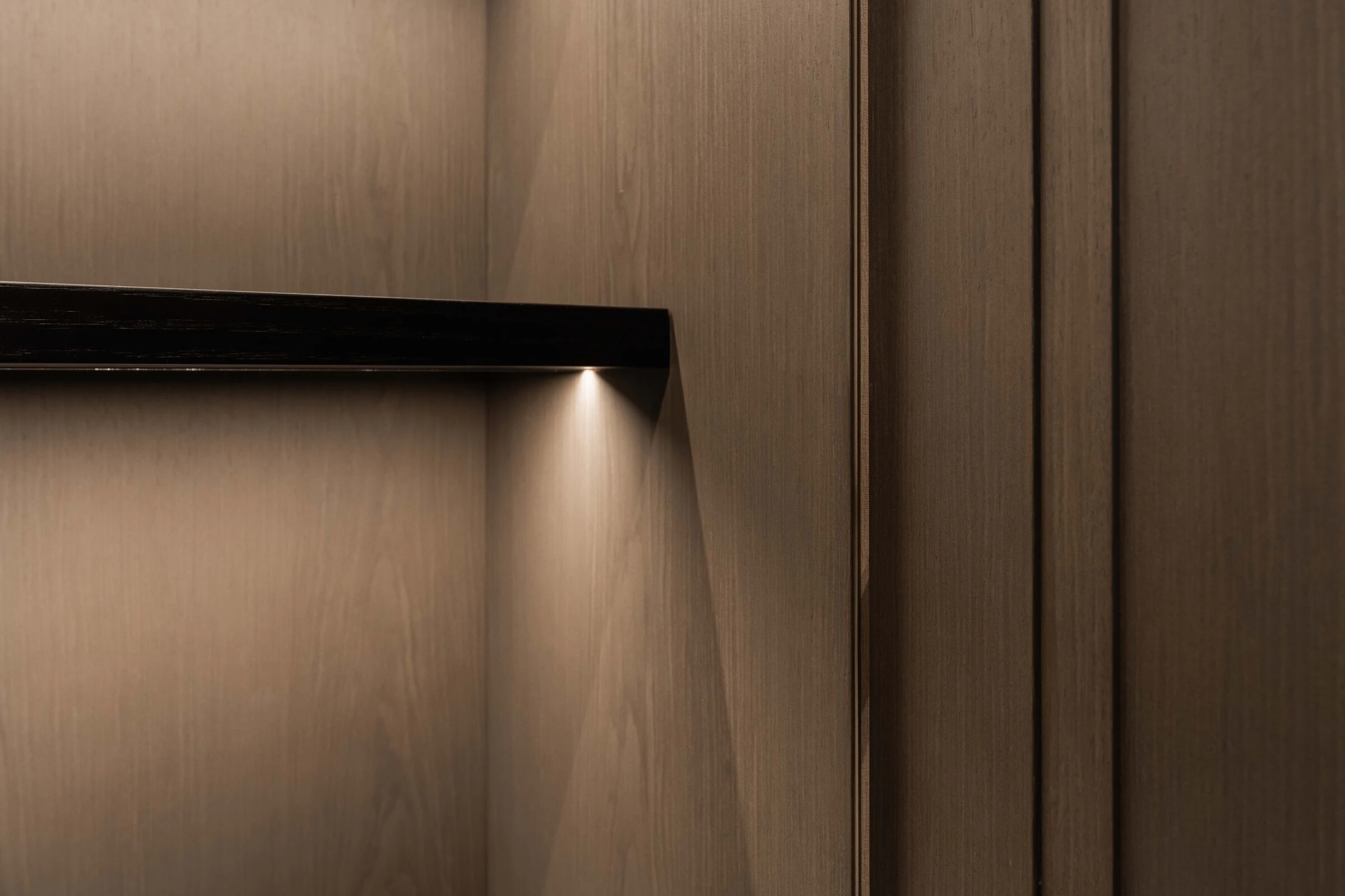 Close-up of veneered panelling, aligned joints and integrated lighting